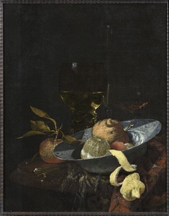 Still life with a porcelain bowl with fruit and glasses on a round marble table by Willem Kalf