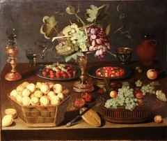 Still life with goblet holder and tazza with grapes surrounded by baskets of fruit