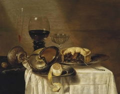 Still life with nautilus cup, pewter plate with lemon, wine glass and Venetian dish with meat pie by Gerret Willemsz Heda
