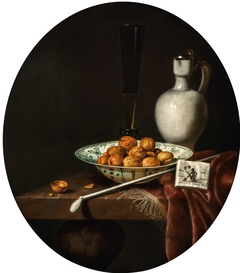Still Life of Walnuts in a Wan-Li Porcelain Bowl, a glazed Earthenware Jug, and a Pipe and Smoking Materials on a partly draped Table by Hubert van Ravesteyn