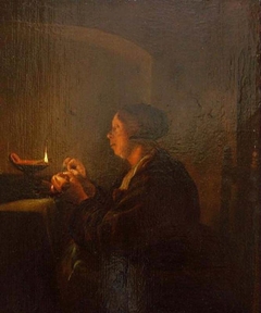 A woman sewing near an oil lamp