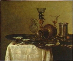 Still life with goblet holder, fallen jug, wine glasses, perfume bottle and pewter dishes by Willem Claesz Heda